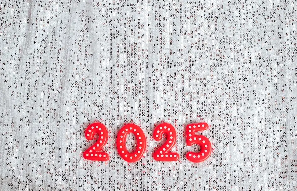 Red ‘2025’ numerals with white polka dots placed on a sparkly silver sequin background.