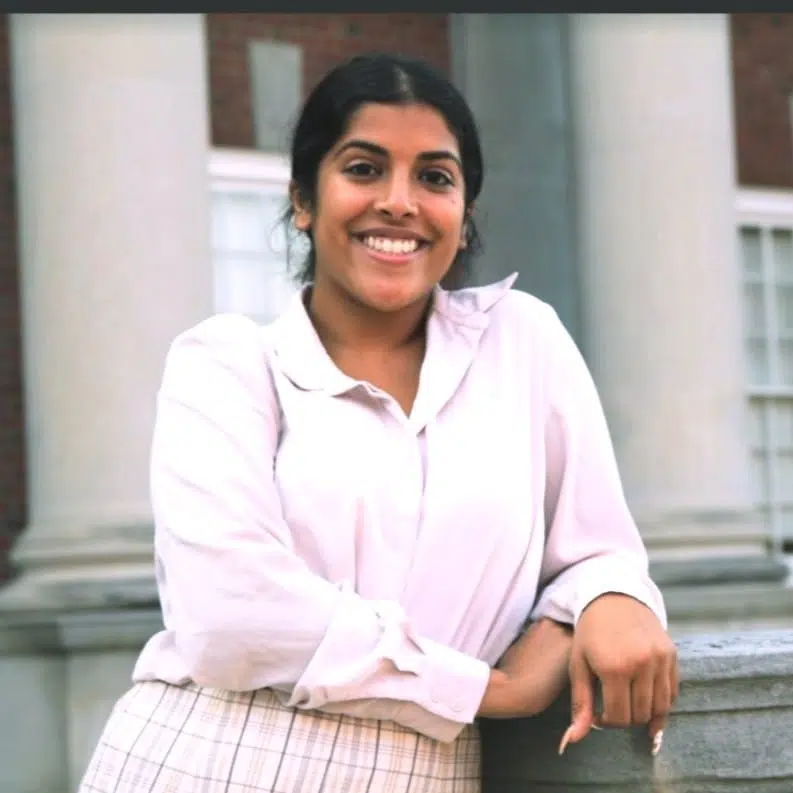 woman with with black hair smiling wearing light pink dress top and pants